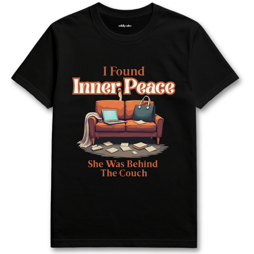 Black t-shirt with a graphic of a couch and text 'I Found Inner Peace She Was Behind The Couch' on a white background - Wildly Calm