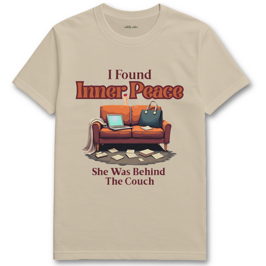 Sand/ Beige t-shirt with a graphic of a couch and text 'I Found Inner Peace She Was Behind The Couch' on a white background - Wildly Calm