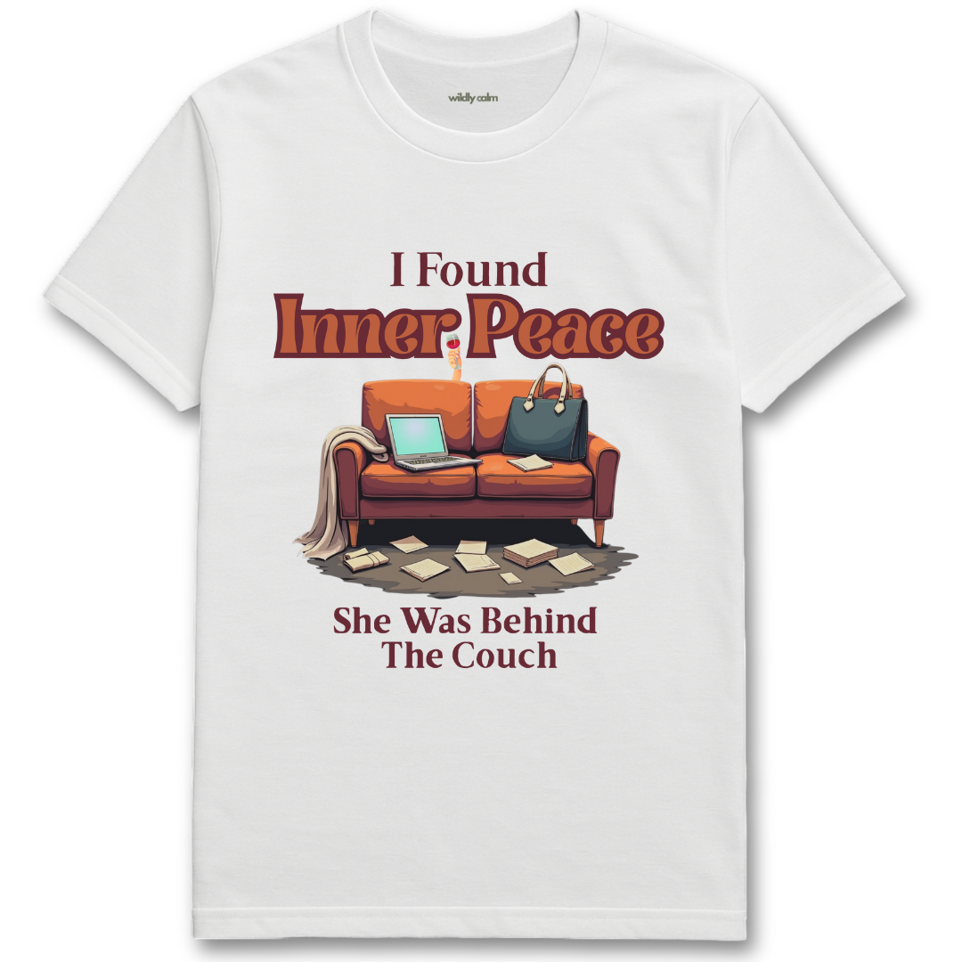 White t-shirt with a graphic of a couch and text 'I Found Inner Peace She Was Behind The Couch' on a white background - Wildly Calm